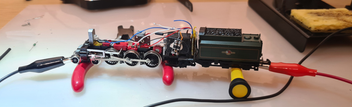 Benchtop testing of the locomotive. The red and black leads clipped onto the wheels connect back to the decoder tester.