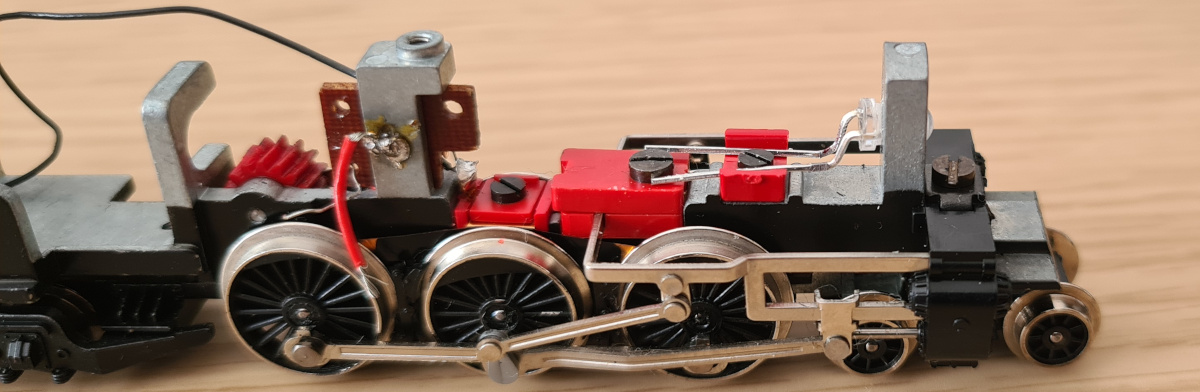 Testing the LED fit. The leads were later trimmed much shorter before soldering the wires on. The bolts and plastic clamps provide a channel beneath the weight for the wires to be routed through. Note that all unnecessary original locomotive parts have been removed.